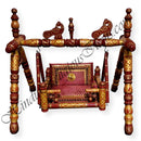 A colorful, traditional wooden palna (cradle) with intricate woodwork and hanging ornamental details.